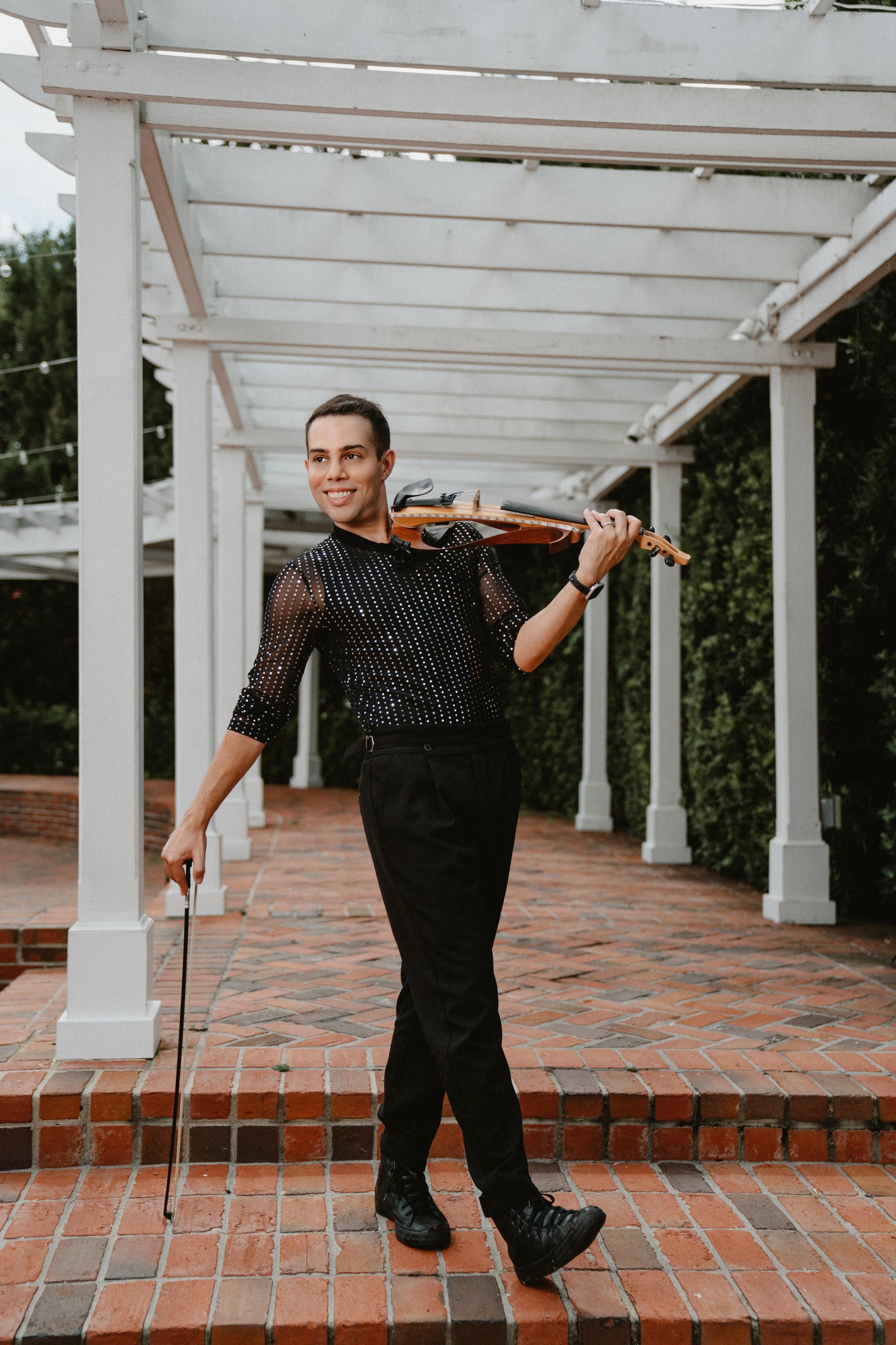 David Chirinos with his violin in a garden pergola