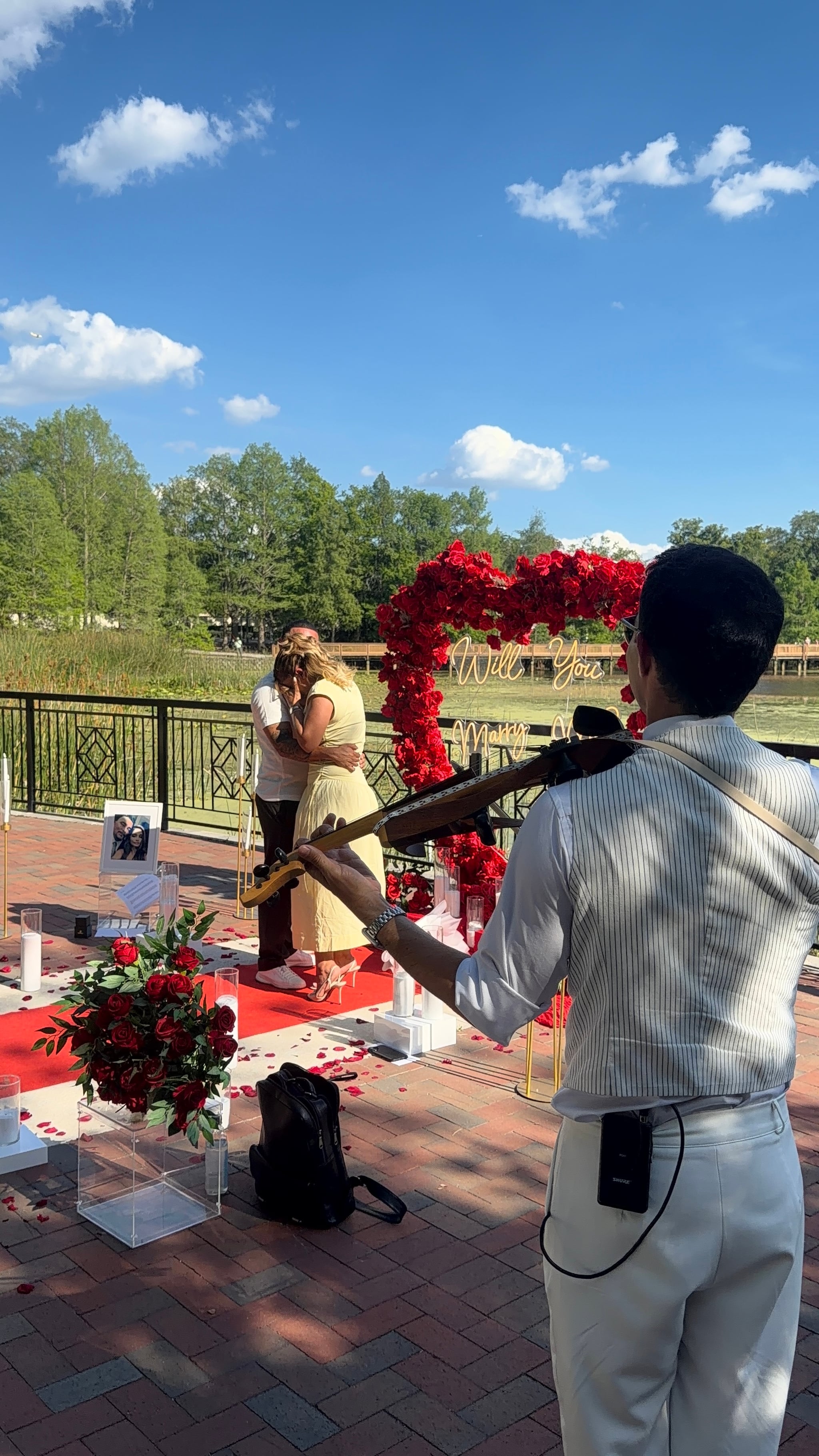 A couple embracing after a proposal, with David Chirinos playing violin